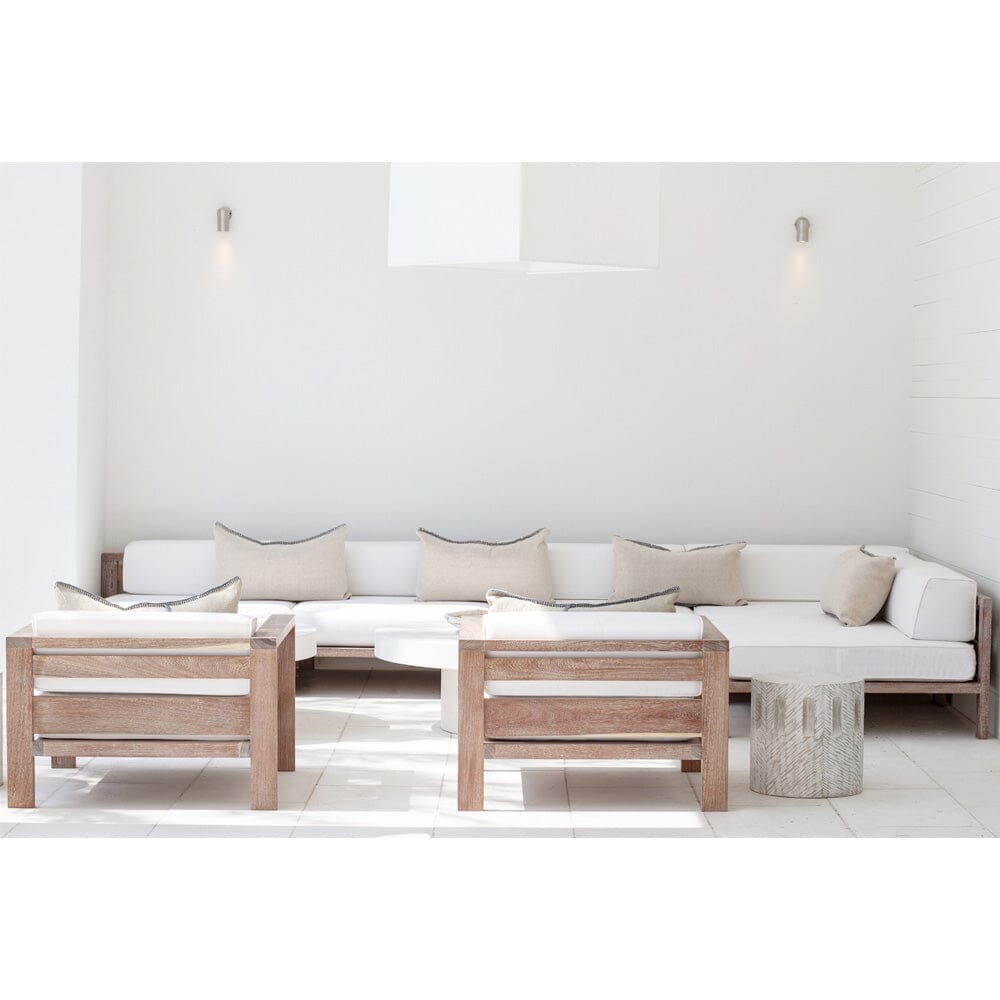 A modular outdoor lounge sectional with a white cushion finish and a natural wood frame, arranged in a spacious indoor setting.