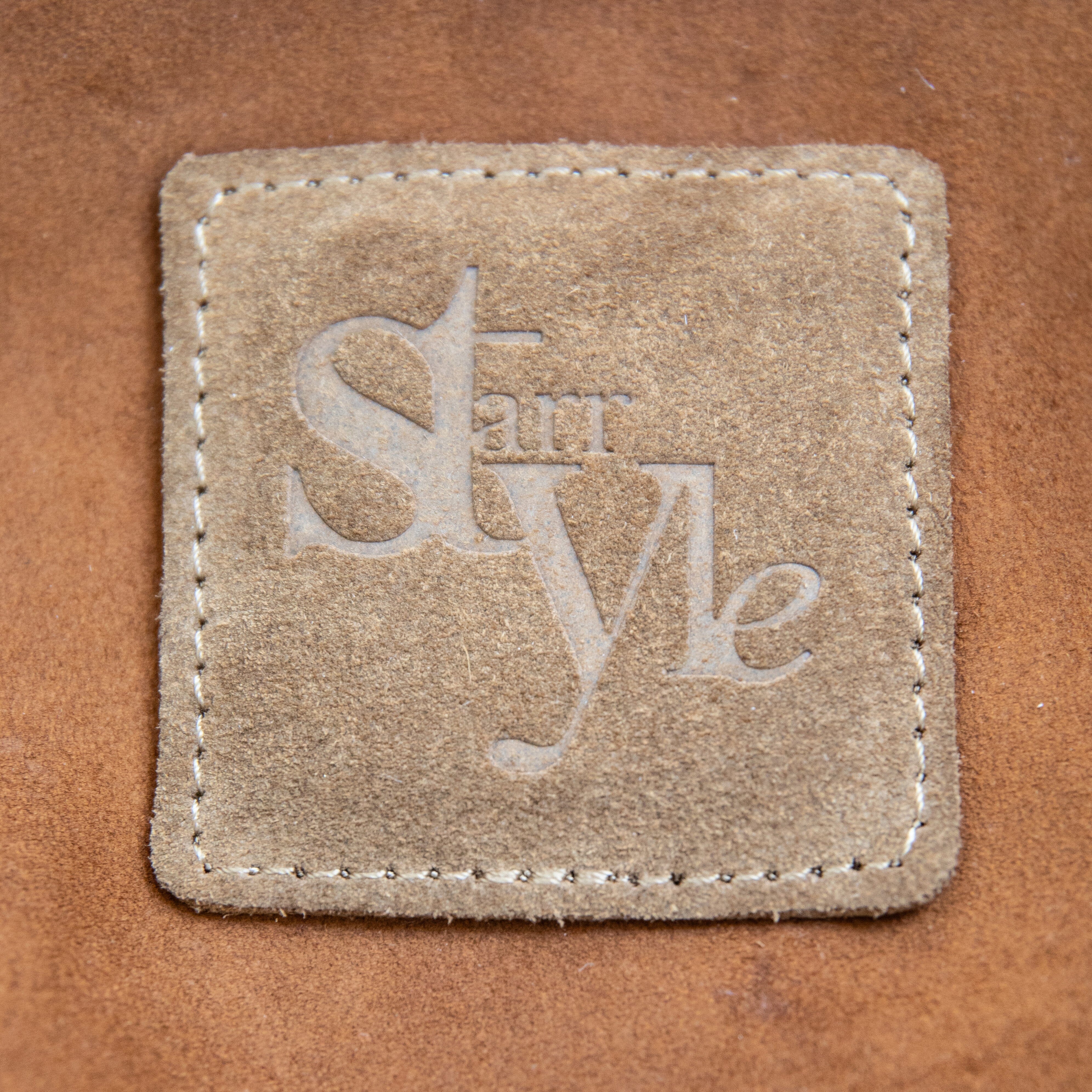 A brown suede crossbody bag with a shoulder strap, displayed against a white background.